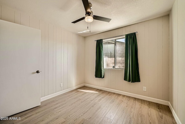 unfurnished room with a textured ceiling, baseboards, a ceiling fan, and wood finished floors