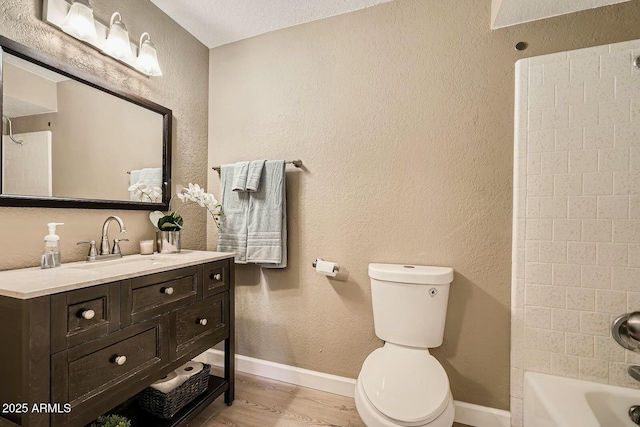 full bath with toilet, wood finished floors, baseboards, and a textured wall