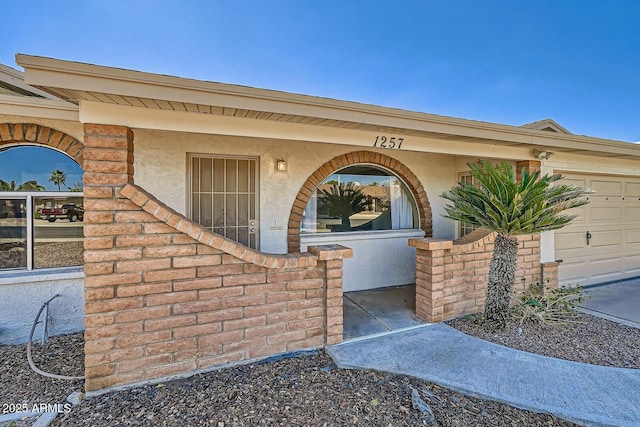 doorway to property featuring an attached garage and stucco siding