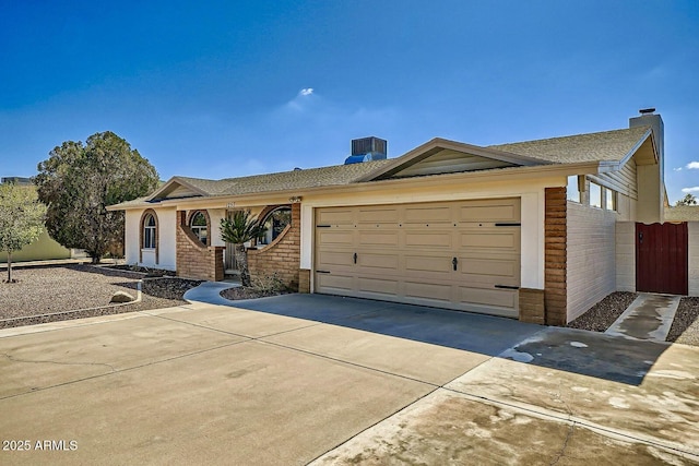 ranch-style house featuring driveway, fence, a garage, brick siding, and a chimney