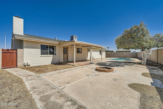 rear view of house featuring a fenced in pool, a chimney, a fenced backyard, a patio area, and a gate