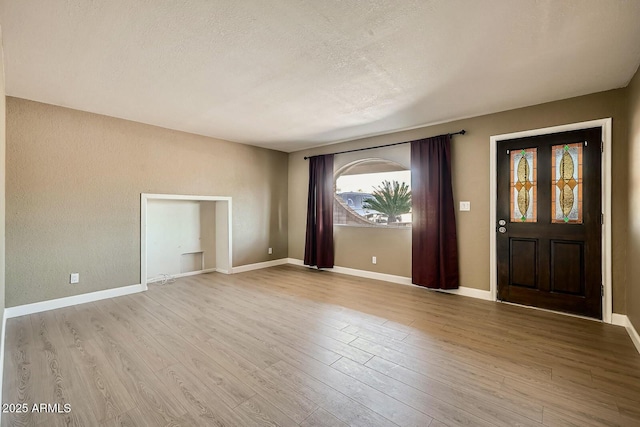 entrance foyer featuring plenty of natural light, a textured ceiling, baseboards, and wood finished floors