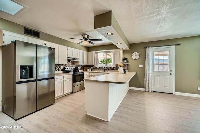 kitchen with visible vents, backsplash, appliances with stainless steel finishes, and a peninsula