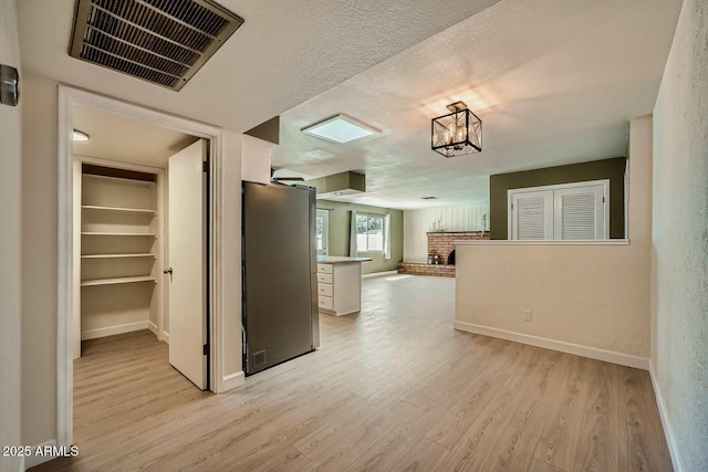 kitchen featuring light wood finished floors, visible vents, white cabinetry, and open floor plan