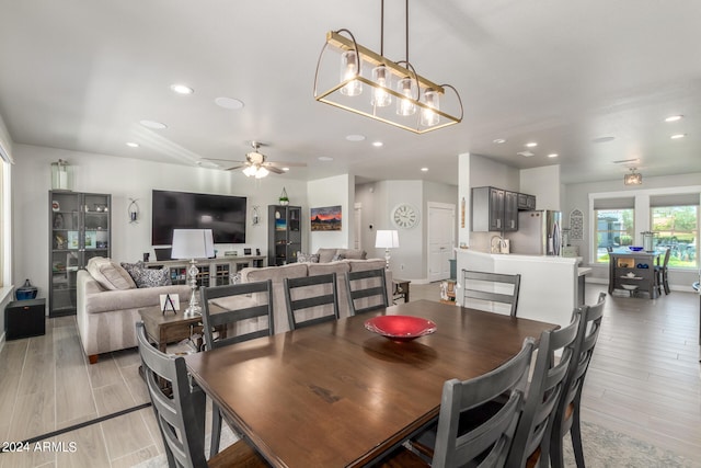 dining room with sink, ceiling fan with notable chandelier, and light wood-type flooring