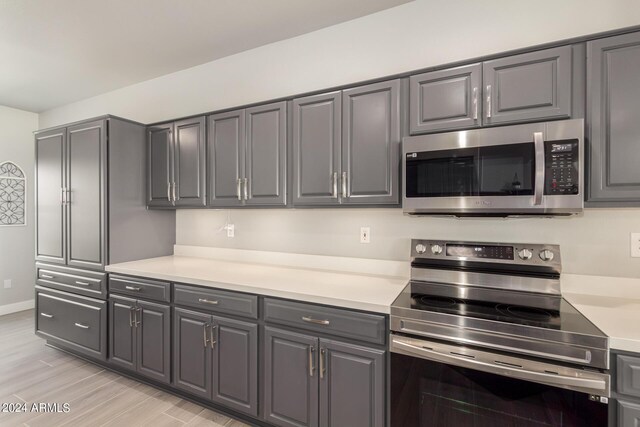 kitchen featuring gray cabinets, appliances with stainless steel finishes, and light wood-type flooring