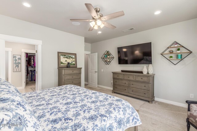 bedroom with a closet, ceiling fan, a spacious closet, and light carpet