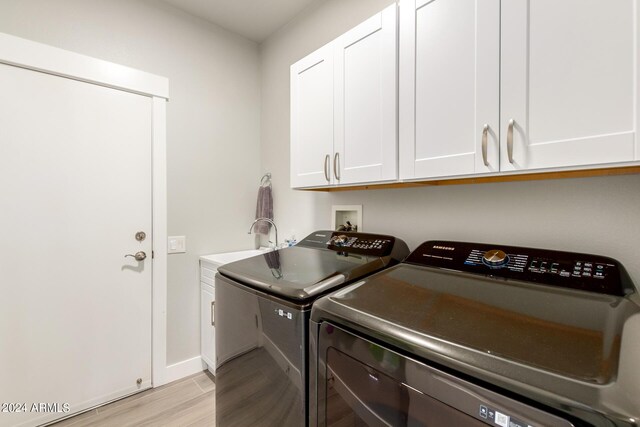 laundry area with cabinets, sink, independent washer and dryer, and light hardwood / wood-style floors