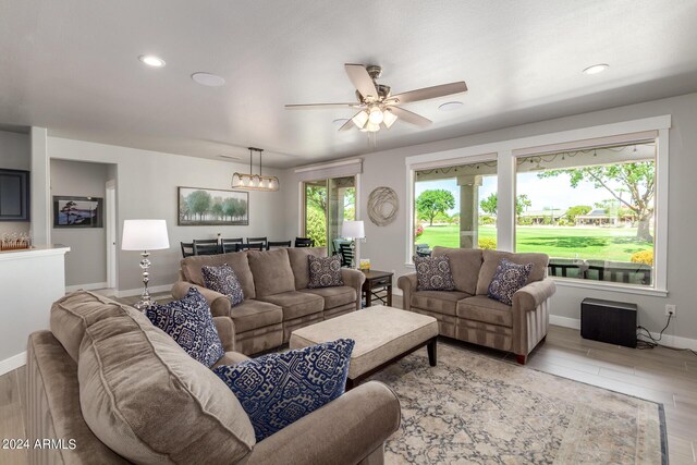 living room featuring ceiling fan with notable chandelier and light hardwood / wood-style floors