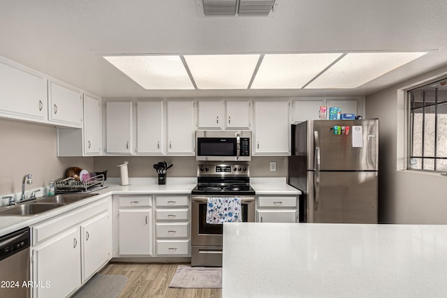 kitchen featuring white cabinets, sink, stainless steel appliances, and light hardwood / wood-style flooring