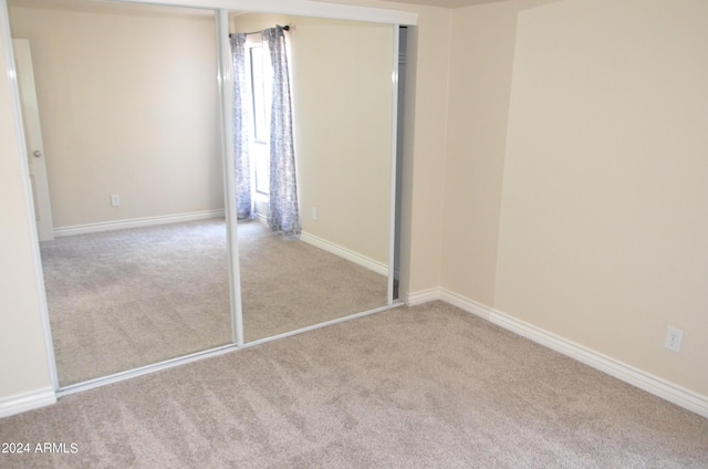 unfurnished bedroom featuring light carpet and a closet