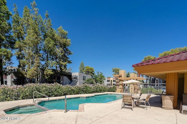 view of swimming pool featuring a patio and a hot tub