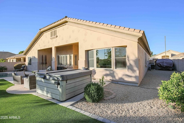 rear view of house with a hot tub and a patio