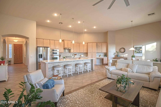 tiled living room with a towering ceiling and ceiling fan