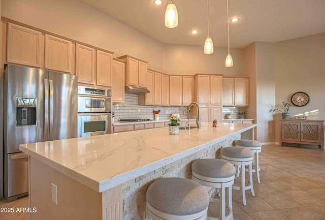 kitchen with pendant lighting, stainless steel appliances, an island with sink, and tasteful backsplash