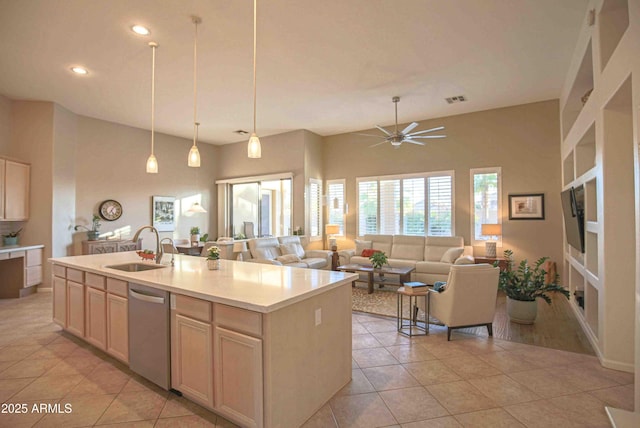 kitchen with light brown cabinetry, dishwasher, sink, a kitchen island with sink, and light tile patterned floors