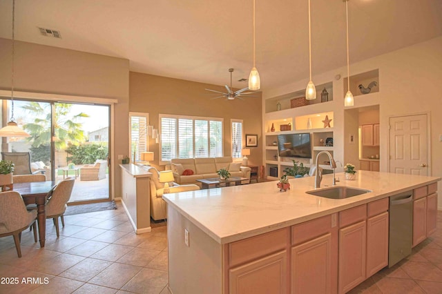 kitchen with pendant lighting, dishwasher, an island with sink, sink, and built in shelves