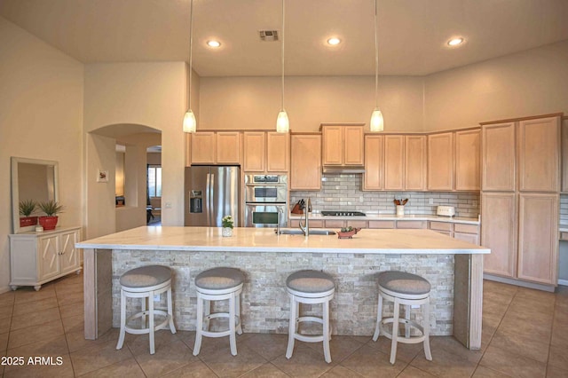 kitchen featuring a kitchen island with sink, decorative light fixtures, decorative backsplash, and appliances with stainless steel finishes