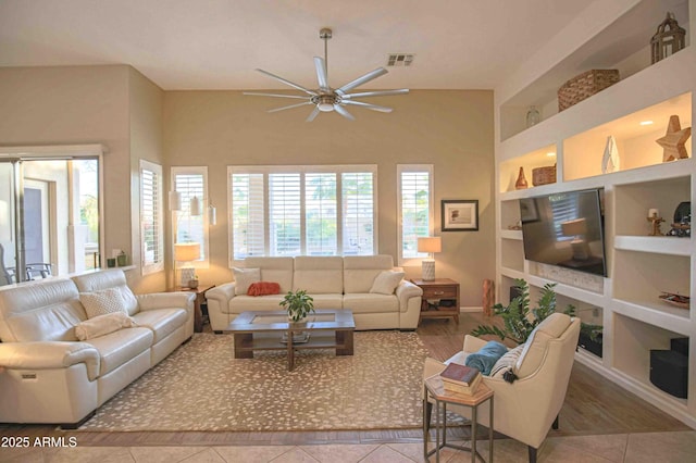 living room with built in shelves, ceiling fan, and tile patterned flooring