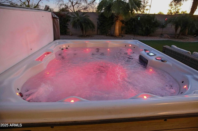 pool at dusk featuring a hot tub