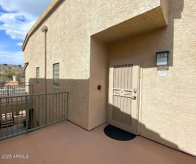 view of exterior entry with stucco siding and a balcony