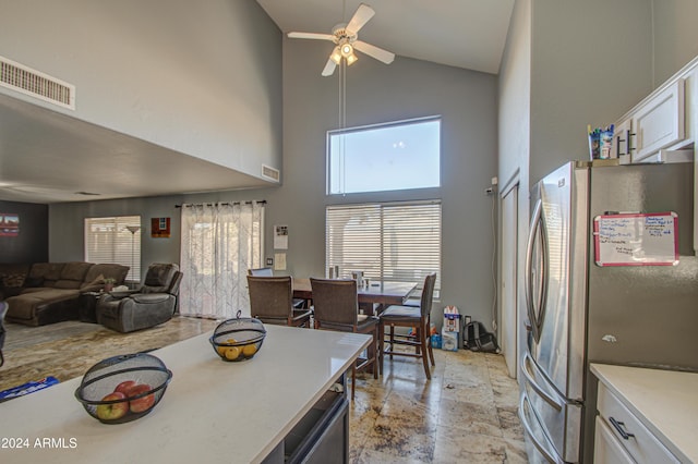 kitchen with white cabinets, stainless steel fridge, high vaulted ceiling, and ceiling fan