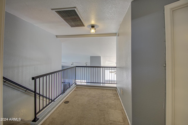 hallway with light colored carpet and a textured ceiling