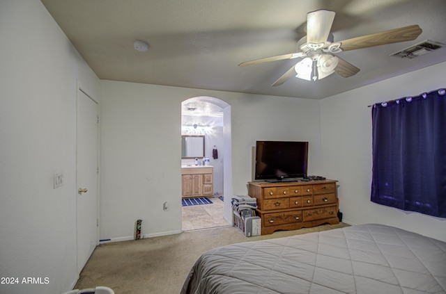 bedroom with light carpet, ensuite bathroom, and ceiling fan