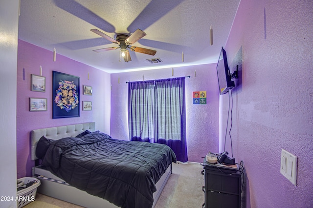 carpeted bedroom featuring ceiling fan and a textured ceiling