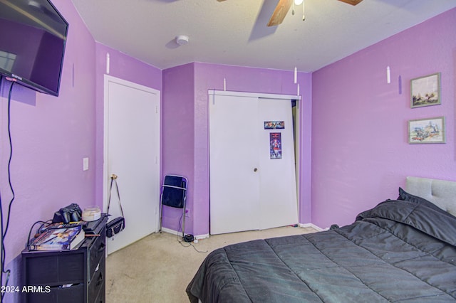 bedroom with a textured ceiling, a closet, light colored carpet, and ceiling fan