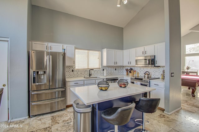 kitchen with a breakfast bar, sink, billiards, appliances with stainless steel finishes, and white cabinetry