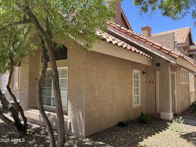 1633 E Lakeside Dr Unit 38, Gilbert, AZ 85234 - view of side of home featuring a chimney, a tiled roof, and stucco siding