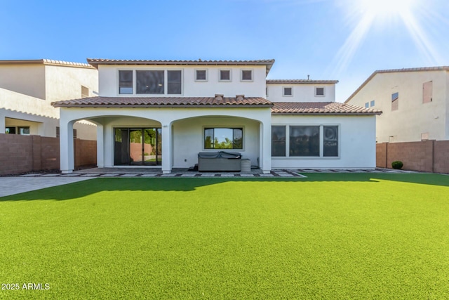 rear view of property with a hot tub and a lawn