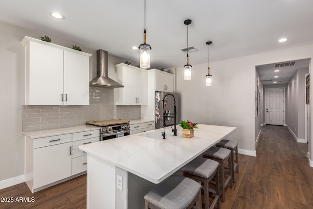 40470 W Agave Rd, Maricopa, AZ 85138 - kitchen with wall chimney range hood, stainless steel appliances, a breakfast bar, a kitchen island with sink, and baseboards