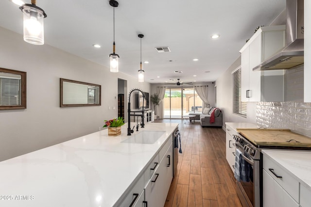 40470 W Agave Rd, Maricopa, AZ 85138 - kitchen featuring stainless steel appliances, wall chimney exhaust hood, a sink, open floor plan, and white cabinets