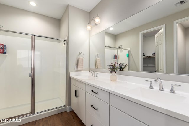 40470 W Agave Rd, Maricopa, AZ 85138 - bathroom featuring a shower stall, wood finished floors, double vanity, a walk in closet, and recessed lighting