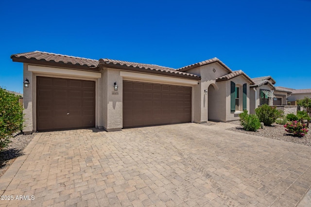 40470 W Agave Rd, Maricopa, AZ 85138 - mediterranean / spanish-style home featuring a garage, stucco siding, a tiled roof, and decorative driveway