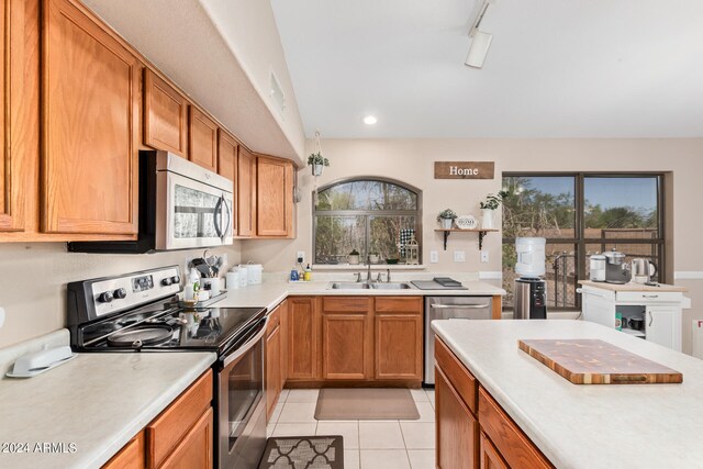 kitchen with appliances with stainless steel finishes, sink, rail lighting, and light tile floors