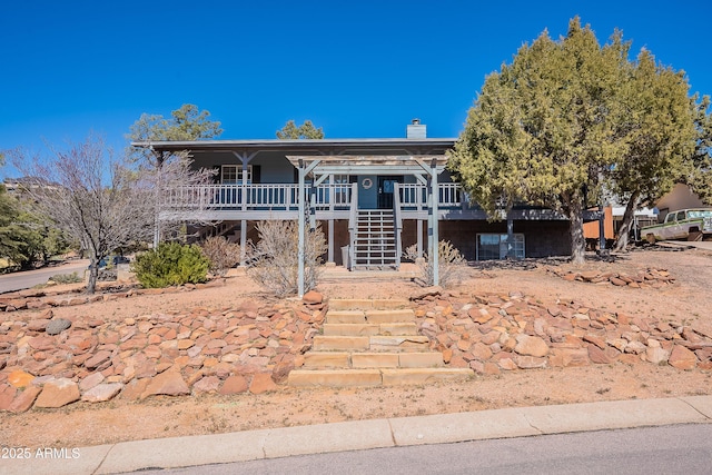 view of front of house with a porch, stairway, and a chimney