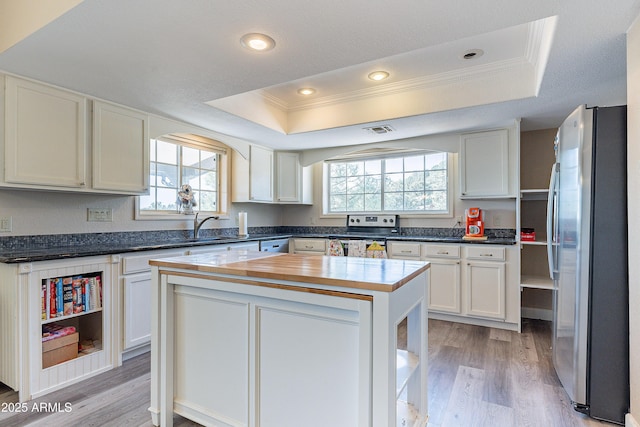 kitchen featuring stainless steel appliances, a sink, visible vents, white cabinetry, and a raised ceiling