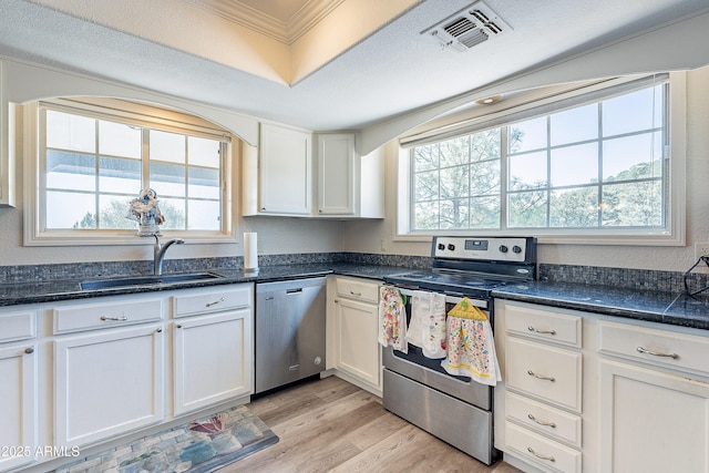 kitchen with visible vents, light wood-style flooring, stainless steel appliances, white cabinetry, and a sink