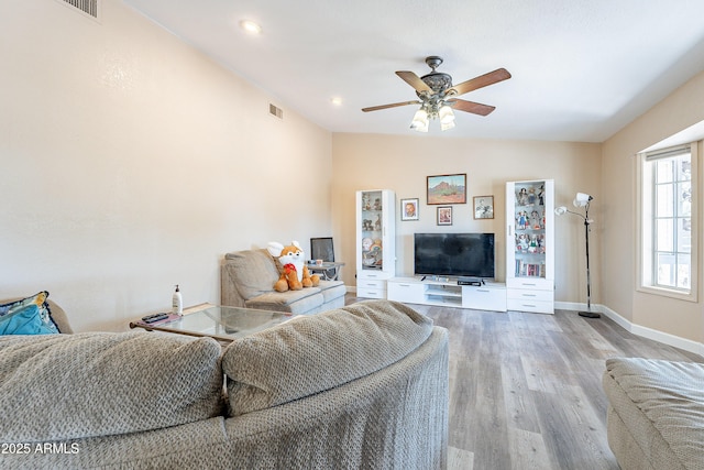 living area with lofted ceiling, ceiling fan, wood finished floors, visible vents, and baseboards