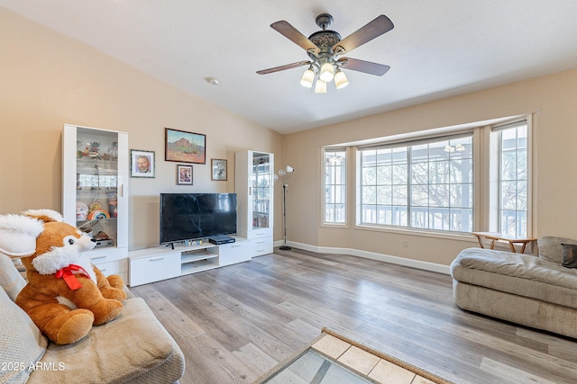 living room featuring lofted ceiling, plenty of natural light, baseboards, and wood finished floors