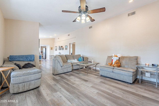 living area featuring visible vents, ceiling fan, baseboards, and wood finished floors