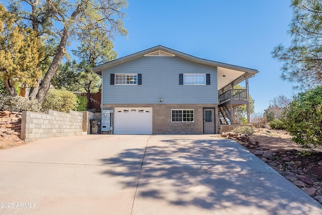 view of front of house featuring stairs, driveway, an attached garage, and fence