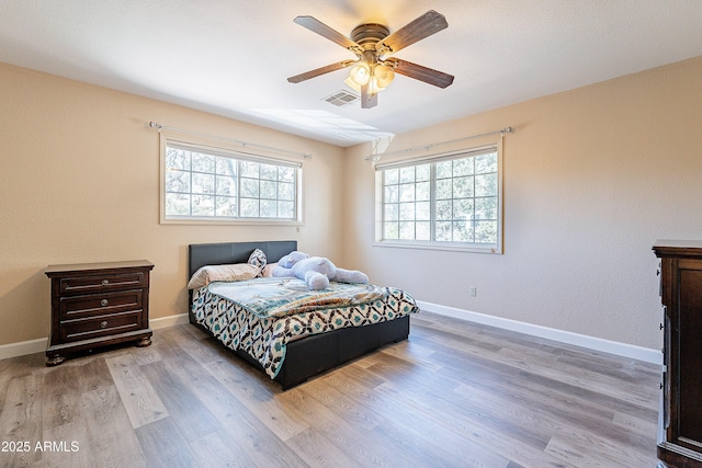 bedroom with visible vents, baseboards, ceiling fan, and wood finished floors