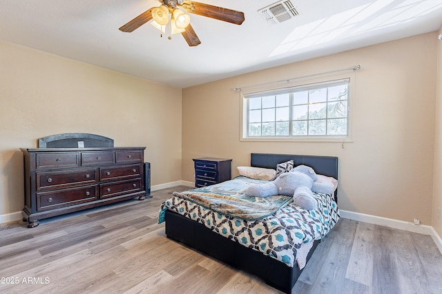 bedroom with light wood-style flooring, visible vents, baseboards, and ceiling fan