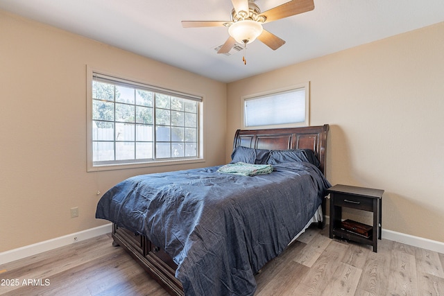 bedroom featuring a ceiling fan, visible vents, baseboards, and wood finished floors