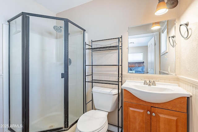 bathroom featuring toilet, a stall shower, a textured wall, and vanity