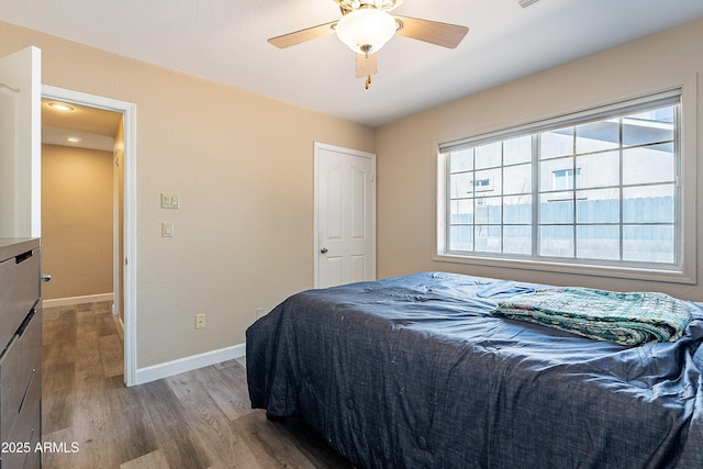 bedroom featuring ceiling fan, baseboards, and wood finished floors